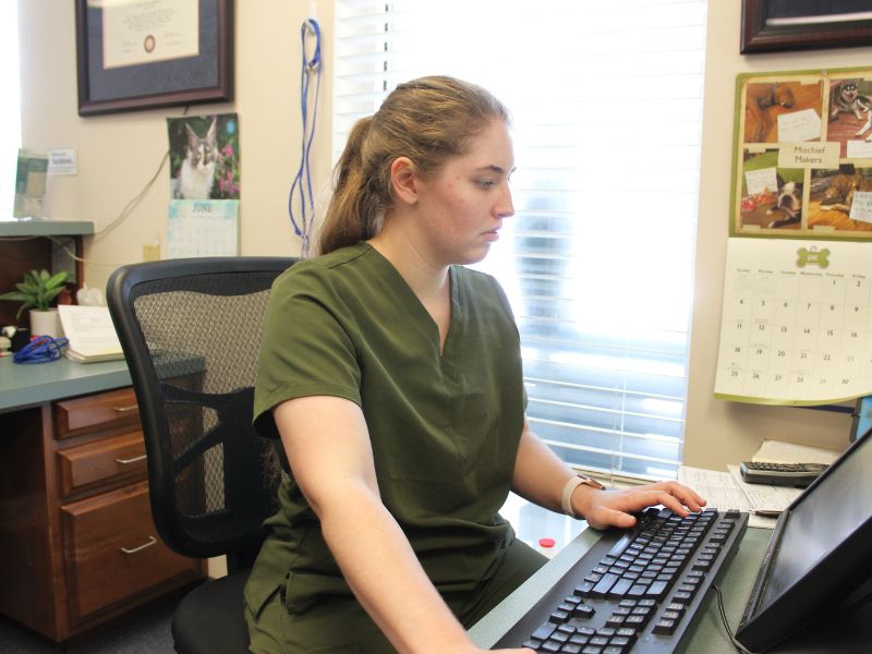 A woman in a green uniform is seated at a desk